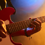 Zbliżenie na ręce grające na czerwonej gitarze elektrycznej w kolorowym świetle.
