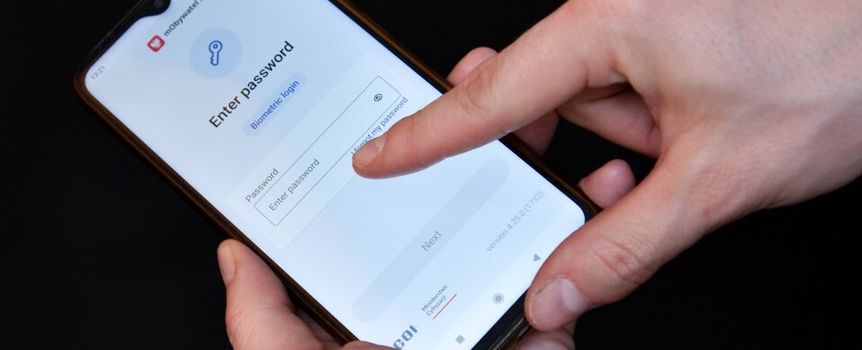 Opis ALT: Osoba wprowadza hasło na ekranie smartfona; jasne tło.