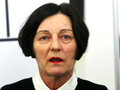 Kobieta o krótkich, ciemnych włosach w czarnej bluzce i białej koszuli, z czerwonymi ustami.