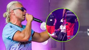 Skolim w sportowej koszulce śpiewa na scenie, obok medycy pomagają mu wejść na scenę..