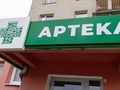 Zielony szyld apteki z białym napisem 