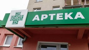 Zielony szyld apteki z białym napisem 
