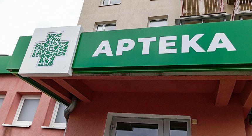 Zielony szyld apteki z białym napisem 