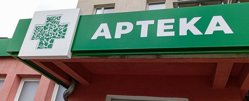 Zielony szyld apteki z białym napisem 