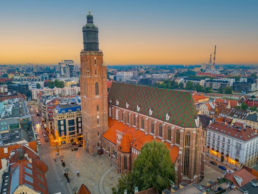Widok na miasto z góry, z wyraźnie widoczną wieżą kościoła i okolicznymi budynkami.