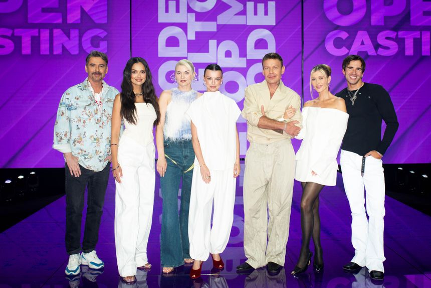 Prowadzący i jury Top Model na scenie, w modnych strojach.