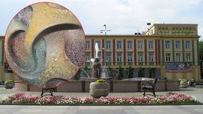 Fontanna w parku, kwiaty w tle, budynek Domu Kultury z reklamami. Dekoracja w kształcie fal.