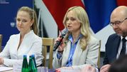Na zdjęciu trzej uczestnicy spotkania. Kobieta z mikrofonem, po lewej w białej bluzce.
