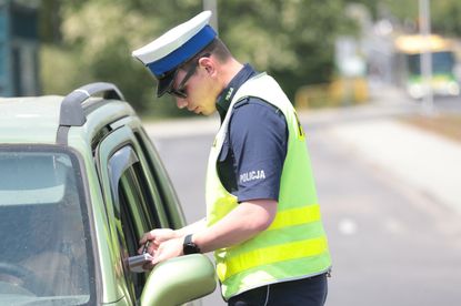 Policjant wręcza mandat - materiał prasowy