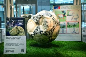 Piłka nożna z mundialu 1986, eksponowana na trawie, wraz z dokumentacją i opisem.