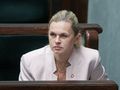 Na zdjęciu widoczna jest kobieta w białej marynarce, słuchająca dyskusji w parlamencie.