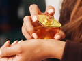 Kobieta aplikująca perfumy z pomarańczowej buteleczki