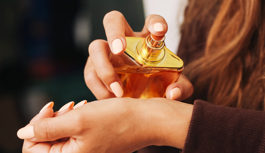 Kobieta aplikująca perfumy z pomarańczowej buteleczki