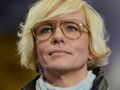 Kobieta z krótkimi blond włosami i dużymi okularami, patrzy w górę.