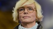 Kobieta z krótkimi blond włosami i dużymi okularami, patrzy w górę.