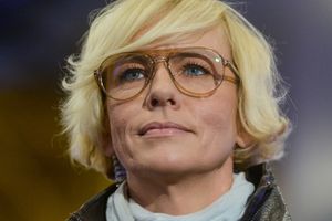 Kobieta z krótkimi blond włosami i dużymi okularami, patrzy w górę.