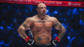 Piotr „Bestia” Piechowiak z tatuażami stoi w klatce MMA, ubrany w rękawice. Tło jasno oświetlone.