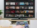 Na ekranie telewizora wyświetla się interfejs Netflix z różnymi filmami i serialami.