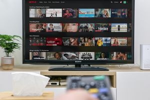 Na ekranie telewizora wyświetla się interfejs Netflix z różnymi filmami i serialami.