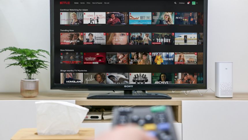 Na ekranie telewizora wyświetla się interfejs Netflix z różnymi filmami i serialami.