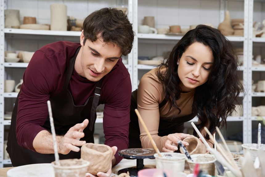Para pracuje nad ceramiką w warsztatach, koncentrując się na formowaniu gliny.