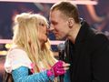 Dwie osoby w blasku świateł, zbliżone do siebie, uśmiechają się i rozmawiają.