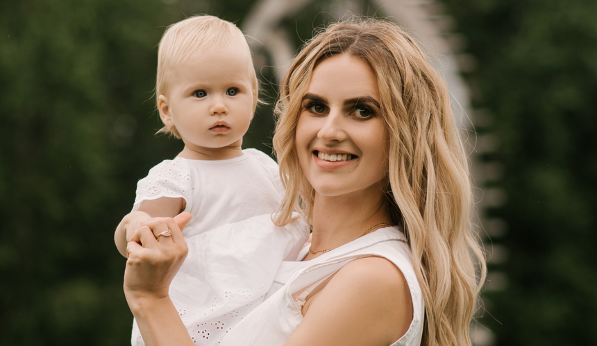 Blondynka w białej sukience z córką na rękach