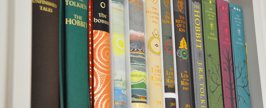 Na zdjęciu widoczne są różne książki J.R.R. Tolkiena na półce, w tym 