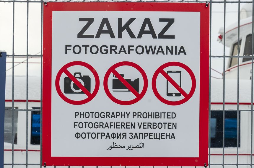 Znak zakazu fotografowania, z symbolami aparatu, kamery i telefonu w okręgach.