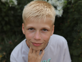 Nastolatek z blond włosami spoglądający w kamerę