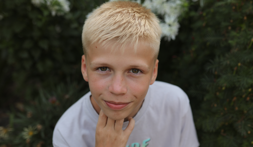 Nastolatek z blond włosami spoglądający w kamerę