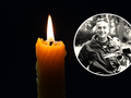 Świeca w ciemności z płonącym ogniem. W tle okrągłe zdjęcie uśmiechniętego mężczyzny.