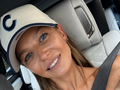 Na zdjęciu uśmiechnięta Anna Lewandowska w czapce z literą C, siedząca w samochodzie.