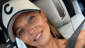 Na zdjęciu uśmiechnięta Anna Lewandowska w czapce z literą C, siedząca w samochodzie.