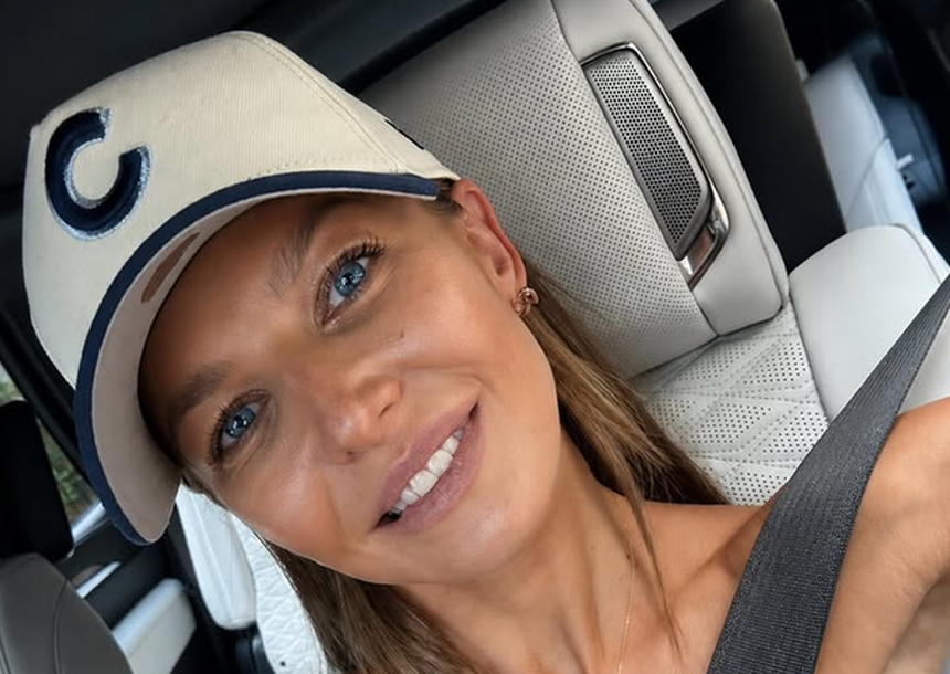 Na zdjęciu uśmiechnięta Anna Lewandowska w czapce z literą C, siedząca w samochodzie.
