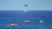 Na zdjęciu widoczny helikopter nad wodą oraz łodzie z pomarańczowymi tratwami ratunkowymi.