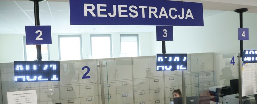 Zarejestrowane stanowiska obsługi w jasnym pomieszczeniu. Napisy informacyjne o numerach.