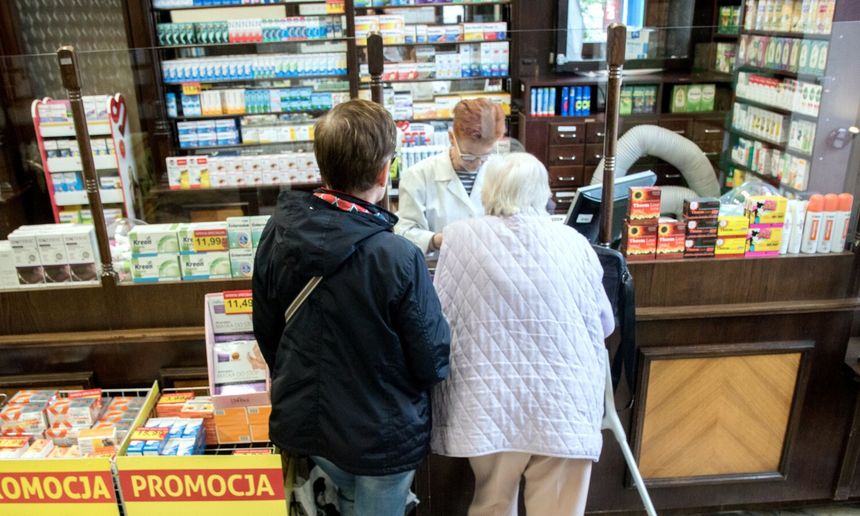 Trzy osoby w aptece, farmaceutka obsługuje dwie klientki przy ladzie. Na zdjęciu nie rozpoznaję polityków.