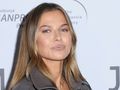 Anna Lewandowska z długimi włosami w jasnej kurtce, stoi na tle białego tła z logiem wydarzenia.