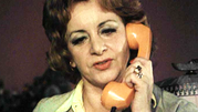 Kobieta z kręconymi włosami rozmawia przez telefon w kolorze pomarańczowym.