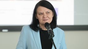 Kobieta z ciemnymi włosami w błękitnej marynarce, mówi do mikrofonu. Tło rozmyte.