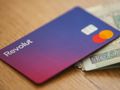 Karta Revolut leży na stole obok banknotów. Kolory karty: fioletowy, czerwony, żółty.