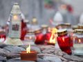 Stos żarówek w różnych kolorach, wśród nich świeca w doniczce na kamieniach.