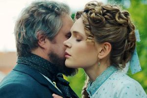 Kobieta i mężczyzna blisko siebie, ich twarze niemal się stykają, w tle zieleń.