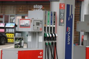 Stacja paliw z dystrybutorami. W tle reklama napoju energetycznego i informacja o tankowaniu.