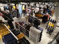 Widok z góry na sklep odzieżowy z różnorodnymi ubraniami na wieszakach i półkach.