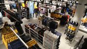 Widok z góry na sklep odzieżowy z różnorodnymi ubraniami na wieszakach i półkach.