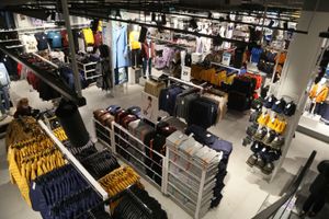 Widok z góry na sklep odzieżowy z różnorodnymi ubraniami na wieszakach i półkach.