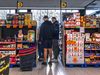 Grupa mężczyzn w supermarkecie, przeszukująca regały z produktami spożywczymi.