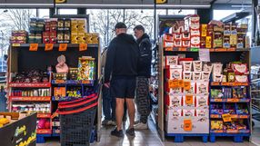 Grupa mężczyzn w supermarkecie, przeszukująca regały z produktami spożywczymi.